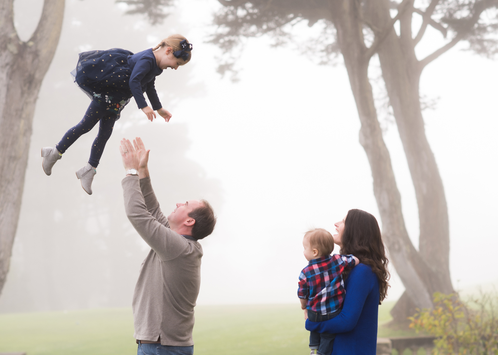 dad catching his daughter with mom and baby brother looking on, foggy San Francisco scene